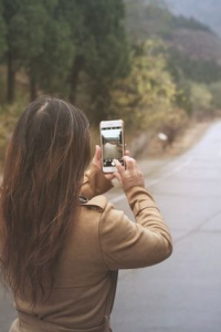 Młoda kobieta trzymająca smartfon skierowany na drogę